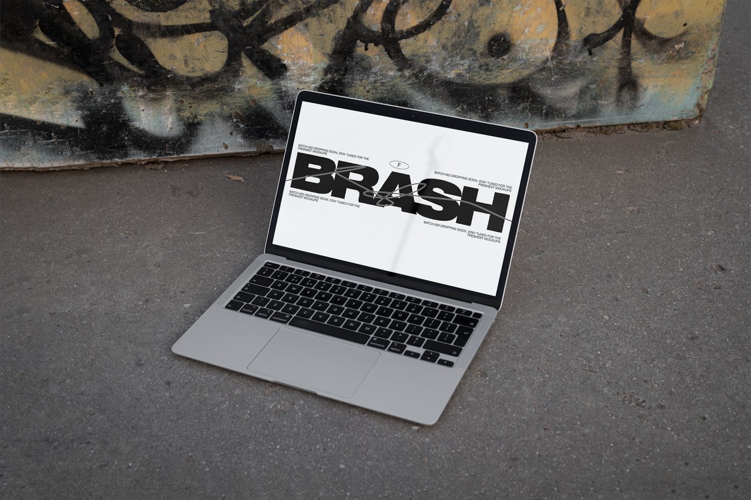 Laptop on urban ground displaying bold font design, ideal for mockup graphics and visual designers seeking contemporary urban aesthetics for projects.